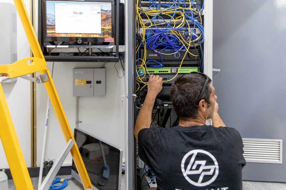 Bpoint technician working on a network rack with recording and switching equipment