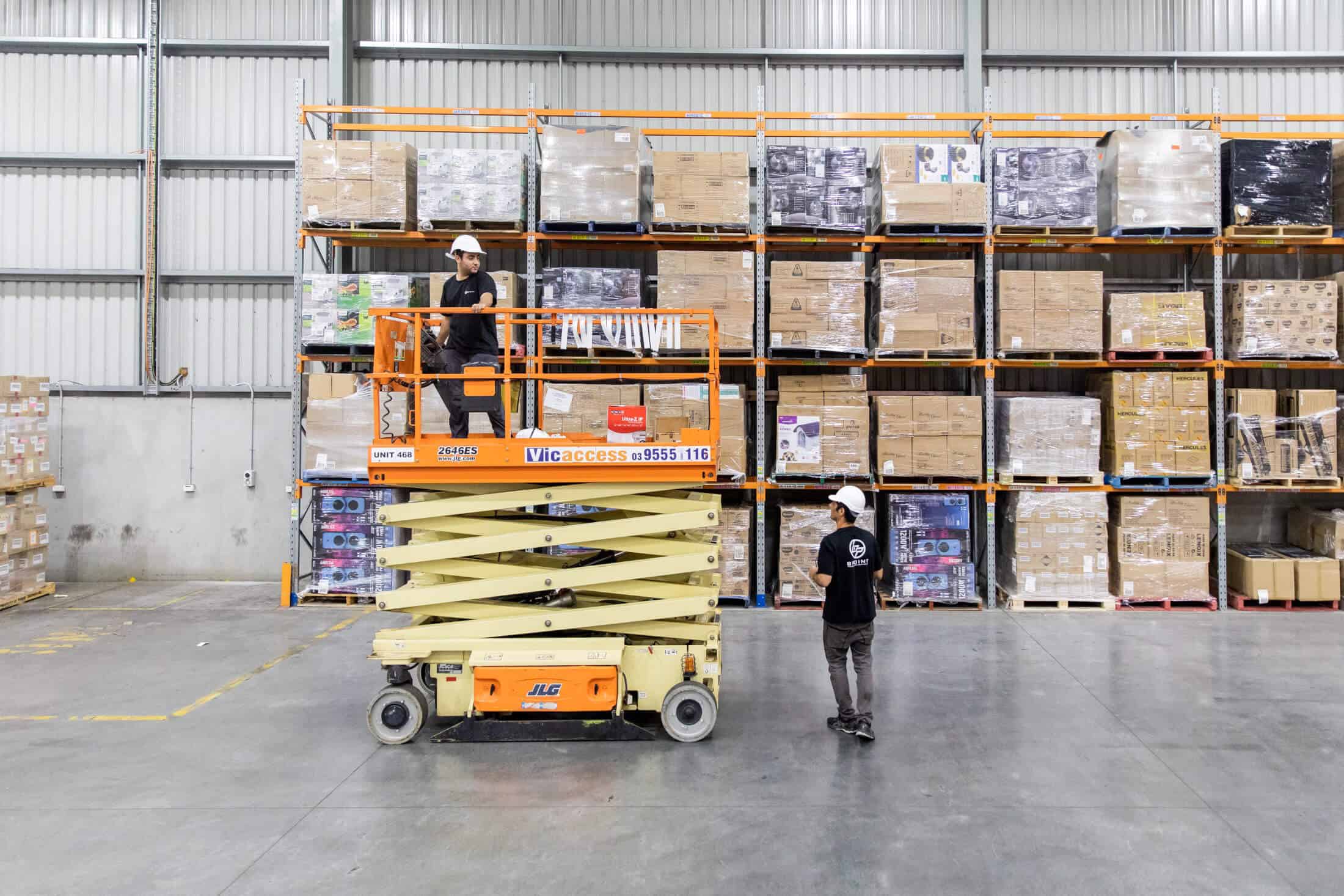 Bpoint technicians installing cameras from a scissor lift in a warehouse