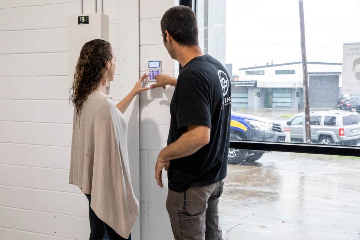 Client using a wall-mounted keypad with a Bpoint technician at a commercial site