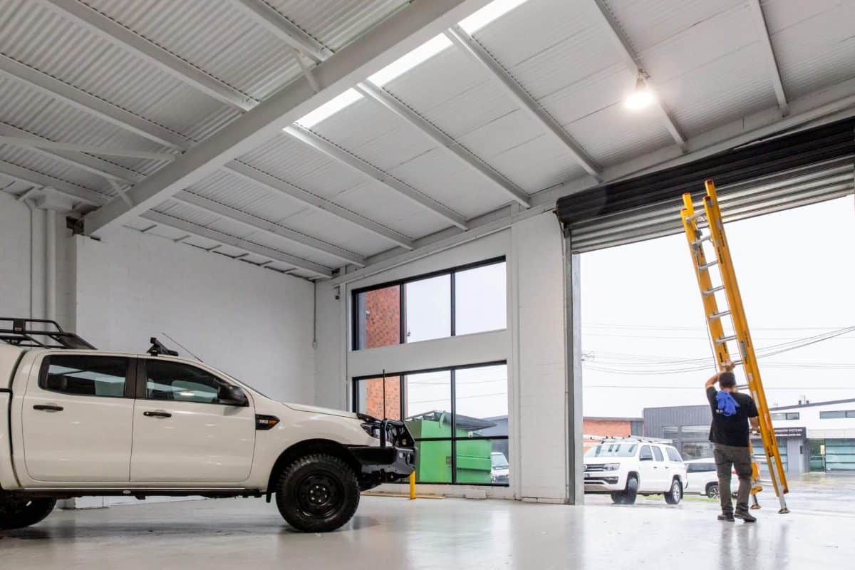 Bpoint technician raising a ladder in a high-ceiling commercial showroom
